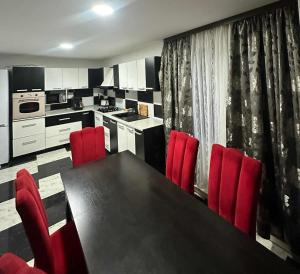 a kitchen with a black table and red chairs at Vila de vacanta Curtea de Arges in Curtea de Argeş