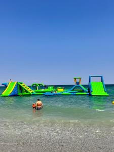 a man in the water at a beach with slides at Dafni Seaside Hotel in Leptokarya