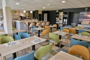 a restaurant with tables and chairs and a bar at Brit Hotel Landivisiau in Landivisiau