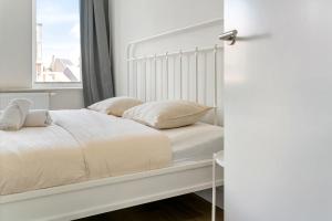 ein weißes Bett mit zwei Kissen und einem Fenster in der Unterkunft Rooftop appartement in Sint-Niklaas