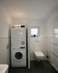 a white bathroom with a washing machine and a toilet at Brise 5 in Büsum