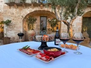 a table with a plate of food and wine glasses at Papalei La Maison in Ragusa