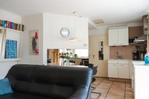 Una sala de estar con un sofá y una cocina. en Gezellig 4 personen woning in Sintmaartenszee aan het strand en natuur!, en Sint Maartenszee