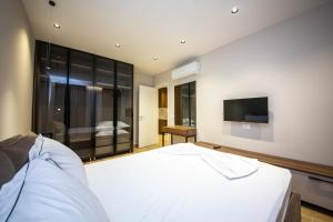 Un dormitorio con una cama blanca y un televisor de pantalla plana. en Apartments Ajdens Place, en Vlorë