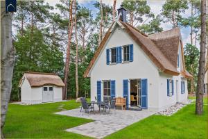 une maison blanche avec des volets bleus et une table dans l'établissement Fischerdorf Ferienhaus Seeadler, à Zirchow