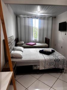 two beds in a room with a window at Pousada Recanto do Mar in Saquarema +158 photos