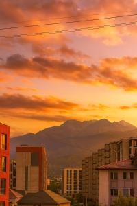 a sunset over a city with buildings and mountains at Cozy Almaty Escape in Almaty