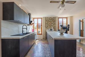 a kitchen with black cabinets and a ceiling fan at Maison Bö in Bossancourt