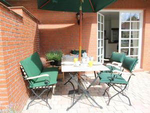 a patio with a table and chairs and an umbrella at Romantik-Residenz Landhaus Greetsiel - B in Krummhörn +7 photos
