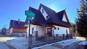 a house with a black roof and a street sign at Apartamenty Tatry in Male Ciche