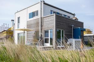 a house on the beach with some chairs and an umbrella at Seaside Corner Tossens - Seaside Corner Tossens - Komfort, Ruhe und Nachhaltigkeit in Butjadingen OT Tossens