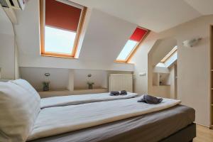 two beds in a room with two windows at Appartamento Quattroporte in Budapest