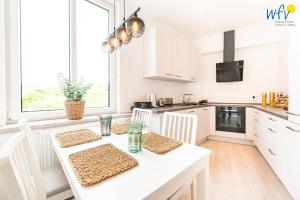 a white kitchen with a white table and chairs at Haus Hummer Köbes Ferienwohnung Paul in Juist
