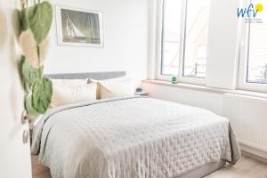 a white bedroom with a bed and a window at Haus Hummer Köbes Ferienwohnung Paul in Juist