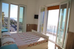 Schlafzimmer mit einem Bett und einem Balkon mit Fenstern in der Unterkunft B&B Tramonto Sul Mare in Salerno