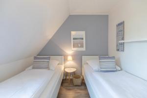 two white beds in a small room with a lamp at Wellenklang in Böhl