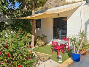 d'une terrasse avec des chaises rouges et une table dans la cour. dans l'établissement Los Nopalitos 1 -Estudio chulísimo súper equipado a 3,5km de Carboneras, à El Llano de Don Antonio