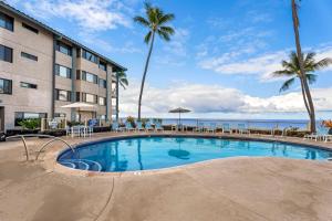 Una piscina frente a un hotel con palmeras. en Kona Reef A6, en Kailua-Kona