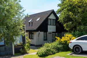 una casa en blanco y negro con un coche aparcado delante en Een Ruime Vakantiehuis aan de kust in het prachtige Sint Maartenszee, en Sint Maartenszee