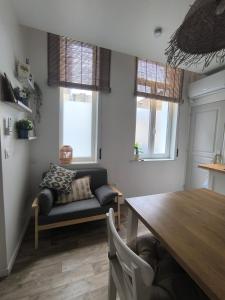 - un salon avec une table, un canapé et des fenêtres dans l'établissement Brise Nacrée proche plage, à Dunkerque