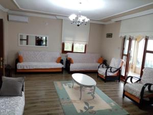 a living room with white couches and a table and chairs at Trabzon Gürbulakta kiralık villa in Trabzon