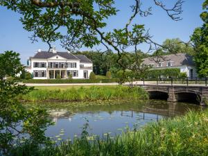 a large white house with a bridge over a river at Boetiek SimonS Loft appartement centrum Brummen in Brummen