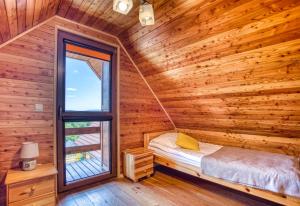 a bedroom with a bed and a window in a log cabin at Domki Eldorado Centrum - Pod kolejką gondolową in Solina
