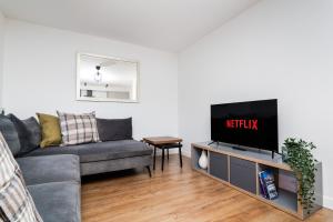 a living room with a gray couch and a tv at 2Bedroom Apartment-Free Parking in Edinburgh
