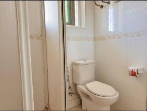 a white bathroom with a toilet and a window at Private Room with attached bathroom at Mikocheni in Nkunjila +9 photos