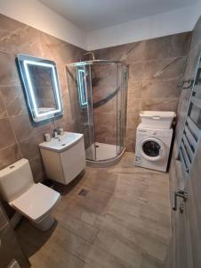 een badkamer met een douche, een toilet en een wasmachine bij Alezzi beach luxury Lidia apartment in Mamaia Nord – Năvodari