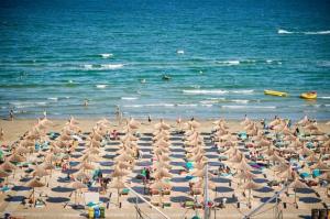 een strand met veel parasols en mensen in het water bij Alezzi beach luxury Lidia apartment in Mamaia Nord – Năvodari