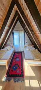 a attic room with two beds and a rug at Agin Konak in Gusinje