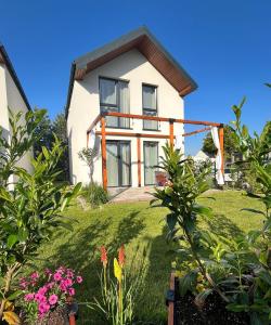 a white house with a yard with flowers at Chillera Domki in Łeba