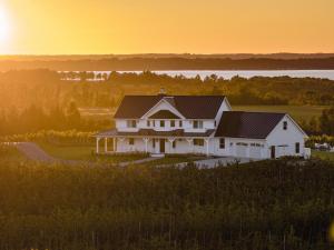 WilliamsburgにあるAnn Riley Farmhouse - Vineyard by Traverse Cityの日没を背景に丘の上の家