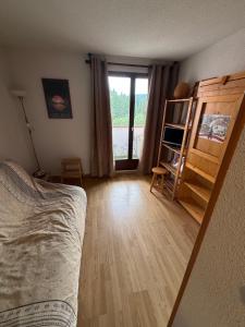 a bedroom with a bed and a room with a window at Studio à la montagne meublé et entièrement équipé in Bellevaux