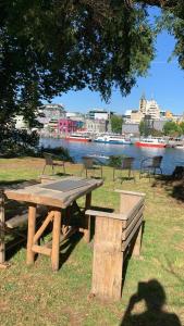 a picnic table and bench next to a body of water at Hospedaje en borde río in Valdivia