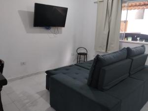 un salon avec un canapé et une télévision à écran plat dans l'établissement Casa em Paraty Portão Vermelho, à Parati