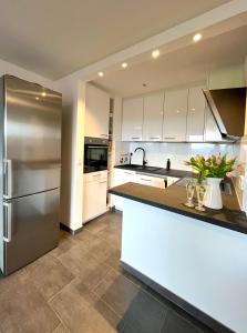 a kitchen with white cabinets and a stainless steel refrigerator at Ferienwohnung Almglück mit Pool uns Sauna, direkt am Skilift in Missen-Wilhams