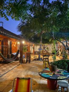un patio con tavoli, sedie e un albero di Canoa Roots Hostel & Camping a Canoa Quebrada