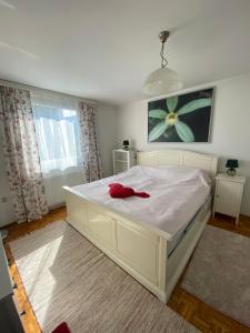 a bedroom with a white bed with a red object on it at Holiday Home Ilidza Ella in Sarajevo