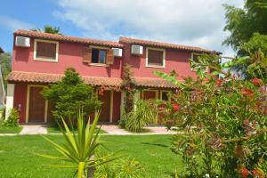 una casa roja con un jardín delante en Alex Katerina Apartments, en Peroulades