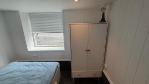 a bedroom with a bed and a cabinet and a window at Arendal Sentrum Ro in Arendal