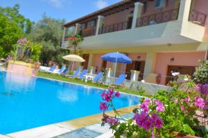 a hotel with a swimming pool with purple flowers at Alex Katerina Apartments in Peroulades