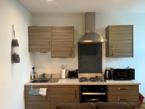 a kitchen with wooden cabinets and a stove top oven at Oasis Urban retreat- Regent Street in Barnsley