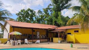 a yellow house with chairs and a swimming pool at CLUBE e HOTEL ARIRANG in Itu