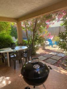 un patio con barbecue, tavolo e sedie di Villa spacieuse avec piscine privee a 150 m de la plage Calvi centre a Calvi