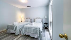 two beds in a bedroom with white walls and wooden floors at 825 Ketch Court at The Sea Pines Resort in Hilton Head Island +12 photos