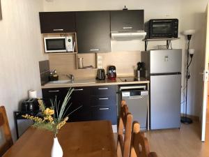 Una pequeña cocina con una mesa y un refrigerador. en T2 tout confort Ax les thermes, en Ax-les-Thermes