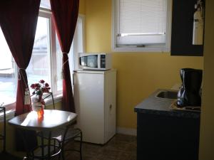 a kitchen with a small table and a refrigerator with a microwave at Motel Rive Du Lac in Saint-Zotique