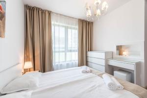 a white bedroom with a bed and a desk at Copacabacum Sea View in Varna City